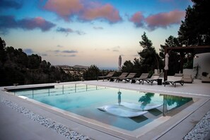Ein Pool ohne Ende mit Liegestühlen, einer Pergola und Blick auf die Landschaft.