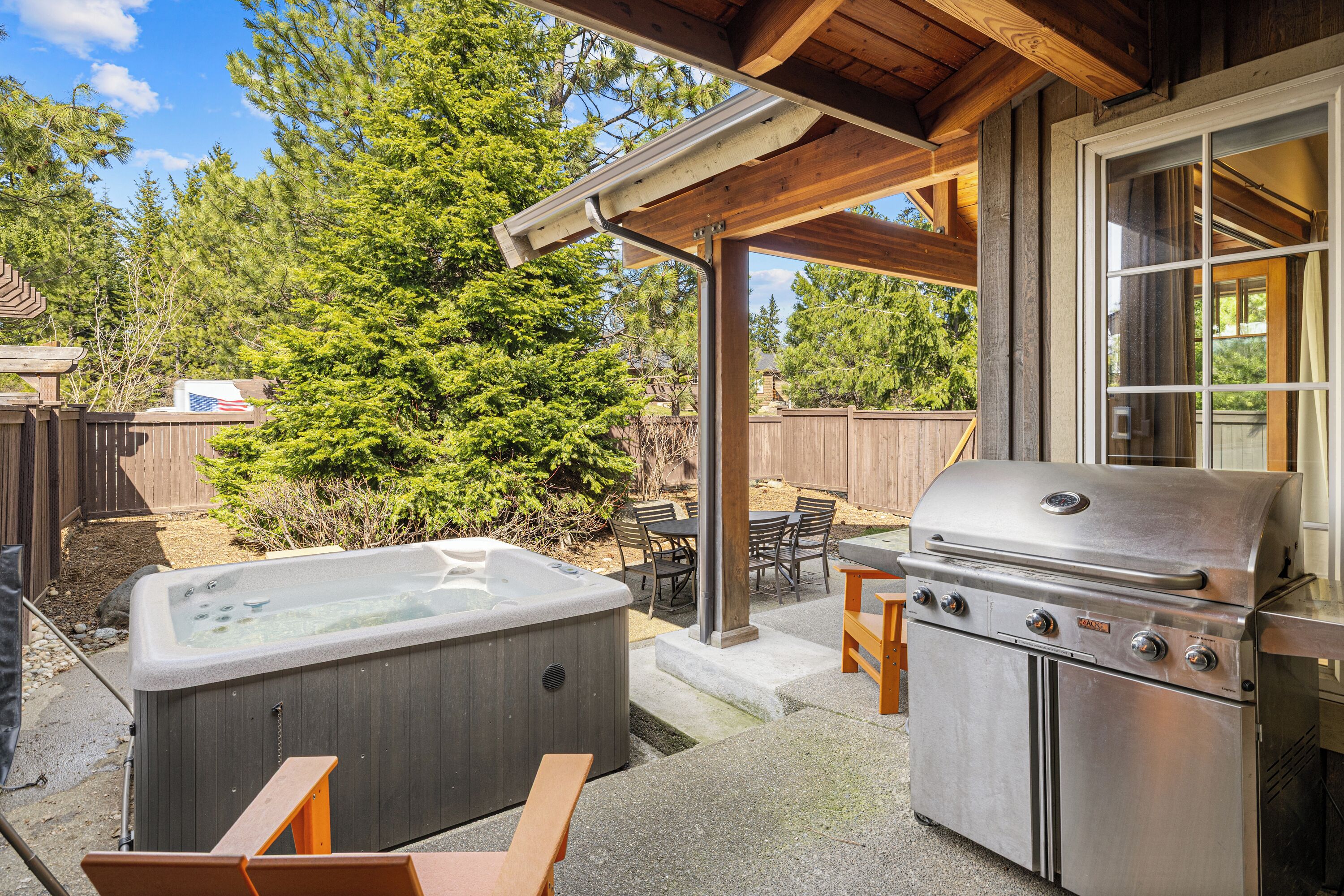 Un jardin avec un jacuzzi, un barbecue et une terrasse en bois.