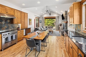 Una cocina con armarios de madera, salpicadero de piedra y una amplia mesa de comedor con sillas.