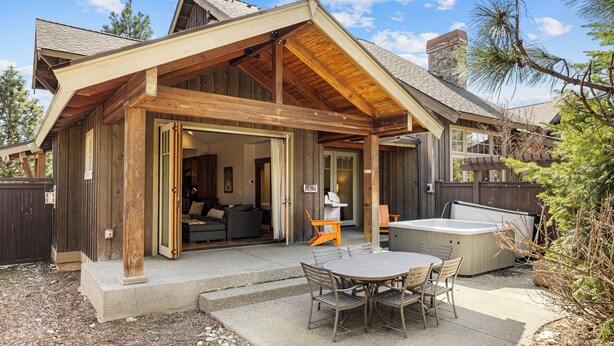 A wooden cabin with a covered patio, a hot tub, and a dining area. - Heart of Suncadia: Fenced Yard, Hot Tub, BBQ, EV Charge, (Cle Elum)