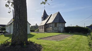 A traditional building with a large tree in the foreground, a grassy yard, and a clear sky. - Gîtes de France® - Le Noyer Gourmand (ILLOIS)
