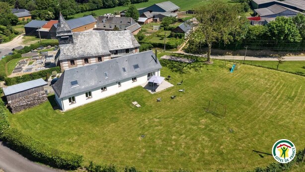 A large estate with a prominent house featuring a steep roof, a spacious lawn, and surrounding farm buildings. - Gîtes de France® - Le Noyer Gourmand (ILLOIS)