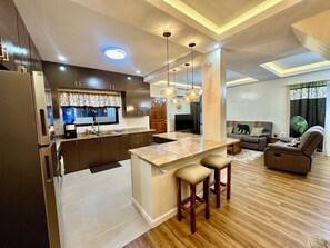 A modern kitchen with dark cabinets, a marble island, and pendant lighting. - BethShalom Guest House by Jeff and Malou, 4 Bedrooms and 2 Bathrooms (Dasmarinas)