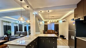 A modern kitchen with dark cabinetry, a marble countertop, and pendant lighting. - BethShalom Guest House by Jeff and Malou, 4 Bedrooms and 2 Bathrooms (Dasmarinas)