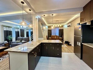 A modern kitchen with dark cabinetry, a marble countertop, and pendant lighting. - BethShalom Guest House by Jeff and Malou, 4 Bedrooms and 2 Bathrooms (Dasmarinas)