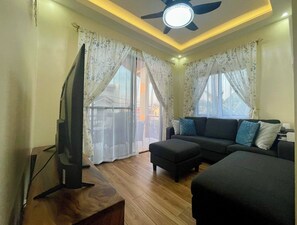 A modern living room with a flat-screen TV, a ceiling fan, a sofa, and a coffee table. - BethShalom Guest House by Jeff and Malou, 4 Bedrooms and 2 Bathrooms (Dasmarinas)