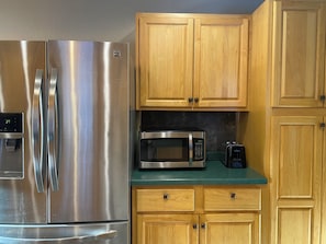 A kitchen with stainless steel appliances, wooden cabinets, and a green countertop.
