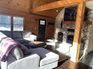 A cozy cabin interior with a stone fireplace, wooden walls, and a sofa.