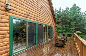 Une cabane en rondins avec une terrasse en bois et une chaise.