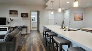 A modern kitchen with a central island, bar stools, and pendant lighting. - Palm Springs Oasis w/Pool & Golf Access (Cathedral City)