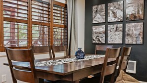 A dining area with a wooden table, chairs, and a vase. - Mt Hood Cabin: River, Trails, Pool, Dog-Friendly (Rhododendron)