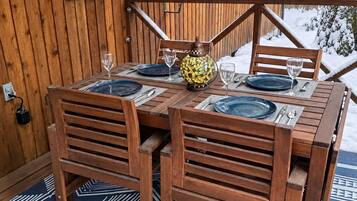 A wooden dining table with chairs, a patterned rug, and a snow-covered exterior.