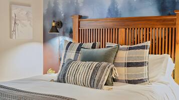 A bed with a wooden headboard, multiple pillows, and a wall mural.