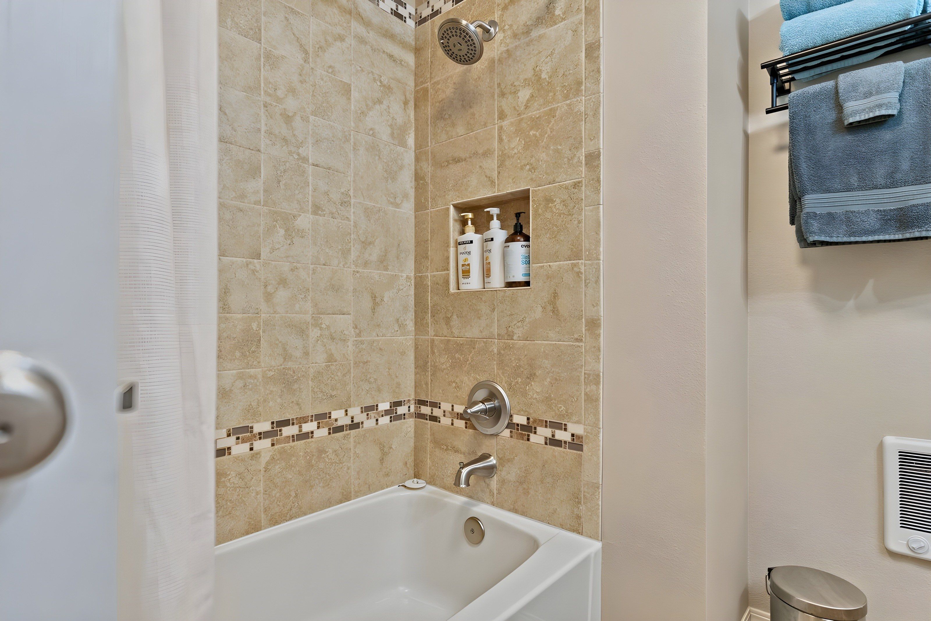 A bathroom with a bathtub, a shower, and a towel rack.