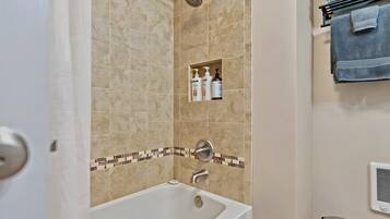 A bathroom with a bathtub, a shower, and a towel rack.