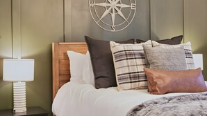 A bed with a wooden headboard, multiple pillows, and a wall-mounted compass decoration. - Mt Hood Cabin: River, Trails, Pool, Dog-Friendly (Rhododendron)