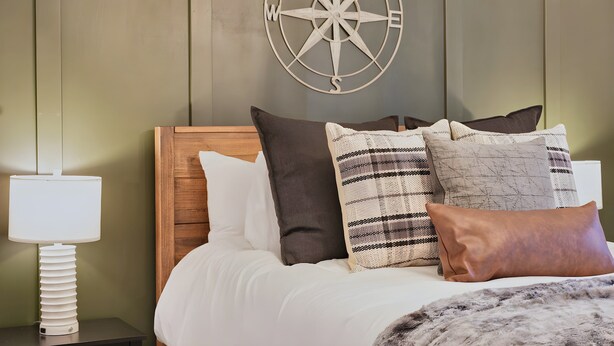 A bed with a wooden headboard, multiple pillows, and a wall-mounted compass decoration. - Mt Hood Cabin: River, Trails, Pool, Dog-Friendly (Rhododendron)