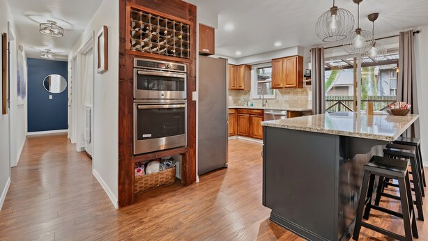 A modern kitchen with wooden cabinetry, stainless steel appliances, and a central island with bar stools. - Mt Hood Cabin: River, Trails, Pool, Dog-Friendly (Rhododendron)