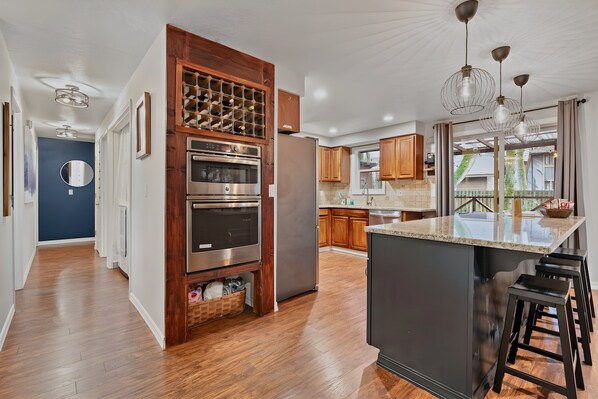 A modern kitchen with wooden cabinetry, stainless steel appliances, and a central island with bar stools. - Mt Hood Cabin: River, Trails, Pool, Dog-Friendly (Rhododendron)