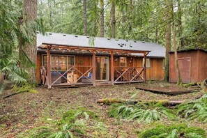 Eine Hütte mit Veranda, Holzfassade und bewaldeter Umgebung.