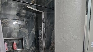 Une salle de bain avec douche, toilettes et lavabo.