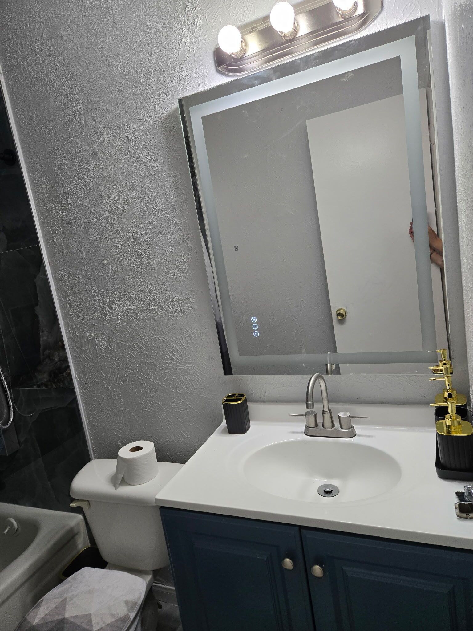 Et badeværelse med en hvid vask, et spejl og et toilet.