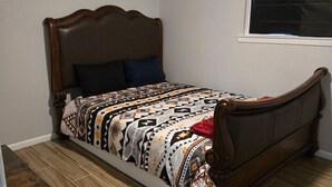Une chambre à coucher avec un lit en bois, une couvre-lit à motifs et une fenêtre avec des stores.