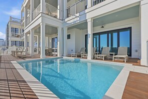 Area della piscina con vista diretta, terrazza in legno e edificio bianco con balconi.