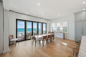 Un interno moderno con zona pranzo, ampie finestre e vista sull'oceano.
