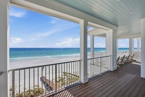 Eine überdachte Holzterrasse mit Blick auf Strand und Meer.