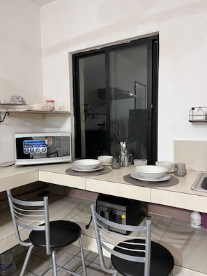 A compact kitchen with a microwave, a sink, and a window. - Minimalist loft in Tec zone with parking (Monterrey)