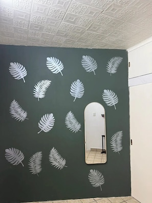A room with a dark green wall, a mirror, and decorative leaf patterns. - Minimalist loft in Tec zone with parking (Monterrey)