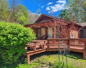 Eine Holzhütte mit Veranda, umgeben von viel Grün.