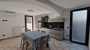 Una cucina compatta con tavolo e sedie, forno integrato e un'ampia porta scorrevole.