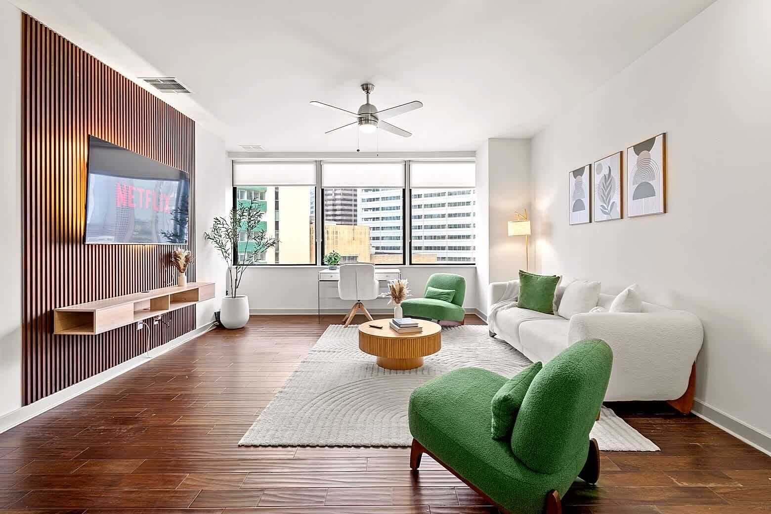 Modern living room with comfortable seating, Smart TV, and large windows that fill the space with natural light.