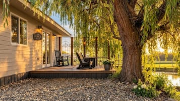 A house with a porch, two chairs, and a large tree.