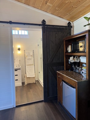 A kitchen with a microwave, coffee maker, and storage shelves.