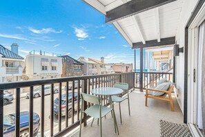 A balcony with a table and chairs, a view of the street, and a building with a balcony. - Walk 1/2 Block to the Beach from this Updated 4BR Coastal Home (Newport Beach)