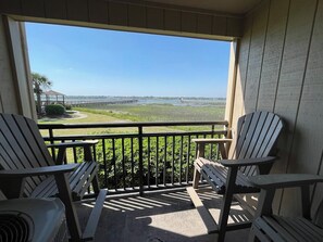 A balcony with Adirondack chairs, a view of a pier, and a grassy area. - Inlet Pointe 23 - Second Row (Channelfront) in Garden City Beach (Garden City Beach)