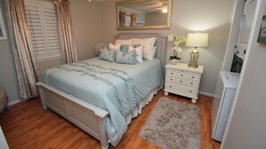 Une chambre à coucher avec un lit, des tables de chevet, un miroir, une lampe et un radiateur.