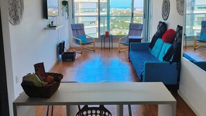 A modern living room with a sofa, chairs, a TV, and a dining area with a table and chairs. - Apartment on Shopping (Montevideo)