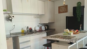 A modern kitchen with white cabinets, a central island with stools, a hanging light fixture, and a sign on the wall. - Apartment on Shopping (Montevideo)