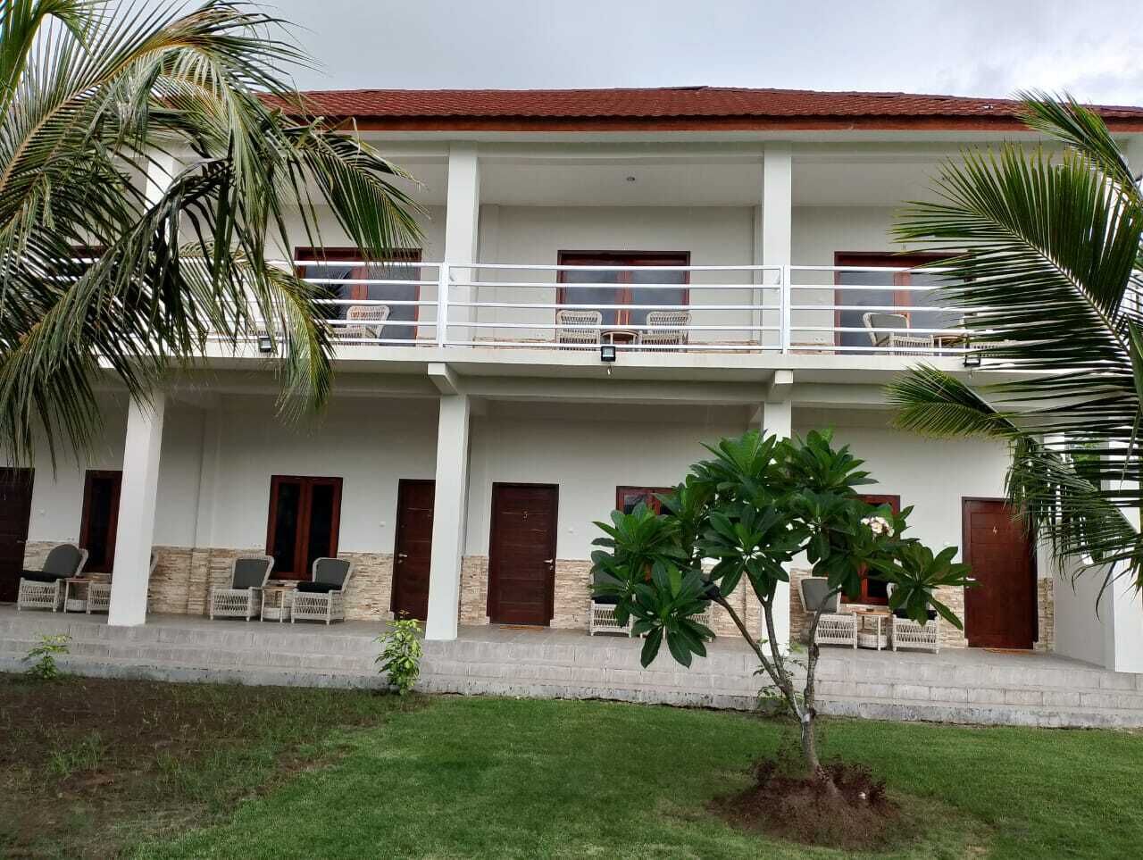 A two-story building with a balcony, multiple doors, and outdoor seating.