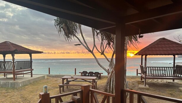 A beachside pavilion with a view of the ocean and a sunset.