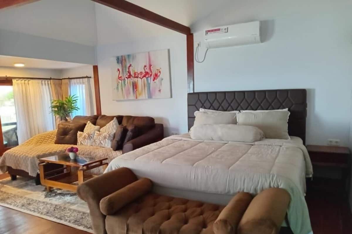 Ett sovrum med en stor säng, en soffa, ett soffbord och en tavla på väggen.