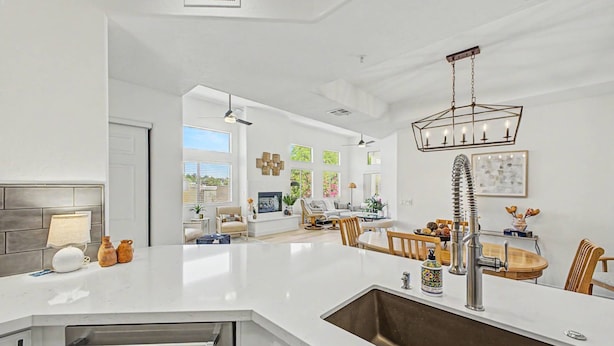 Una cocina moderna con una isla central, un comedor con mesa de madera y una sala de estar con sofá y televisor.