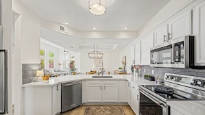 Una cocina moderna con armarios blancos, electrodomésticos de acero inoxidable y una isla central.