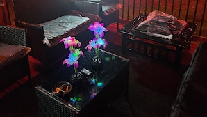 Un'area esterna con mobili in vimini, un tavolo con un vaso di fiori e luci decorative.