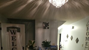 Un soggiorno con camino, un cartello di benvenuto, un lampadario e una parete con la scritta casa dolce casa.