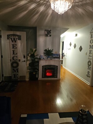 Ein Wohnzimmer mit Kamin, einem Willkommensschild, einer Kandelaber und einer Wand mit der Aufschrift 'Home sweet home'.